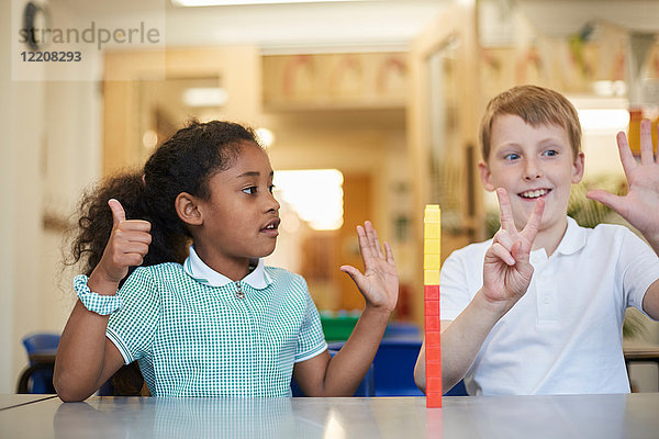 Schüler und Mädchen zählen in der Grundschule im Klassenzimmer auf Finger
