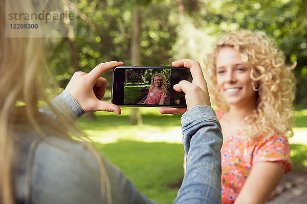 Frau fotografiert einen Freund mit einem Smartphone