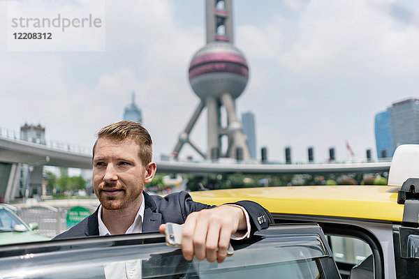 Junger Geschäftsmann steigt am Finanzzentrum Shanghai aus gelbem Taxi aus  Shanghai  China