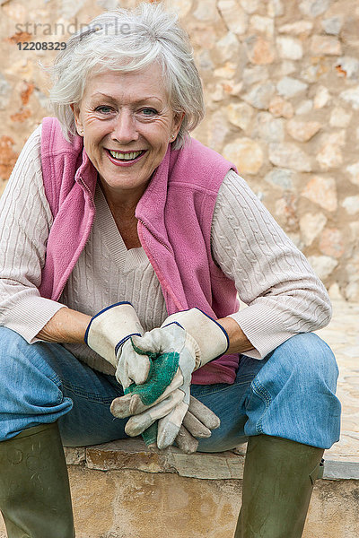 Porträt einer älteren Frau im Freien  die Gartenhandschuhe trägt