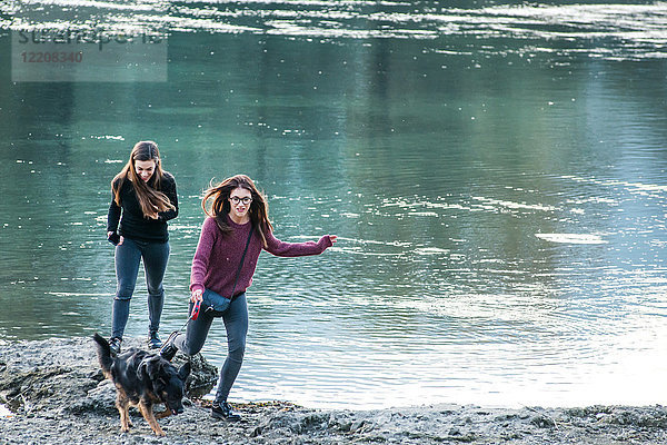 Zwei junge Frauen rennen mit Hund am Fluss  Calolziocorte  Lombardei  Italien