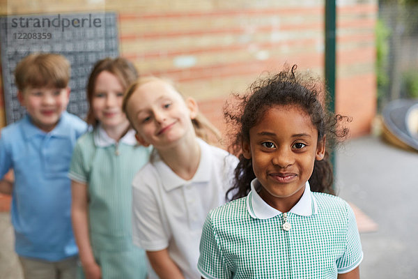 Schulmädchen und Jungen stehen vor dem Grundschulgebäude  Porträt