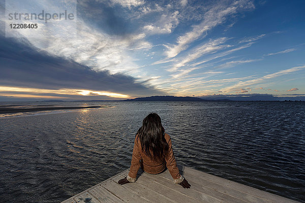 Junge Frau schaut bei Sonnenuntergang vom Pier hinaus  Tarragona  Katalonien  Spanien