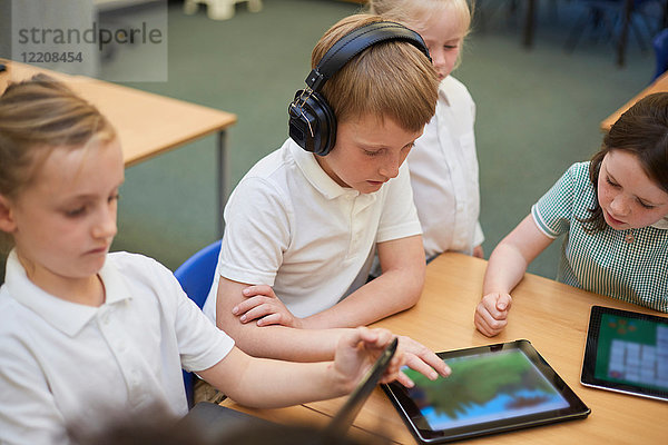 Schülerinnen und Schüler sehen sich in der Grundschule digitale Tablets im Unterricht an