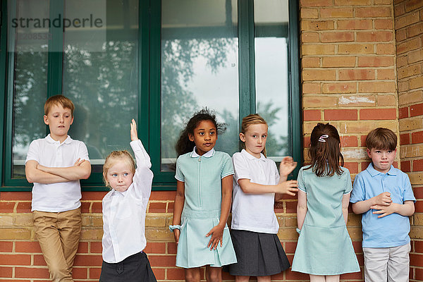 Schulmädchen und Jungen stehen vor dem Grundschulgebäude