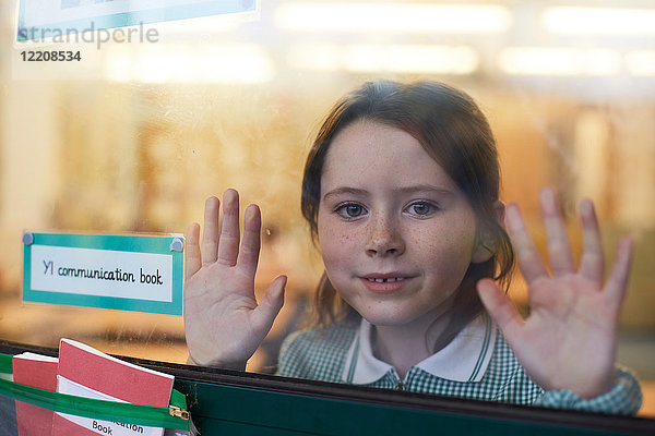 Porträt eines Schulmädchens mit Händen am Klassenzimmerfenster in der Grundschule