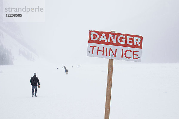 Gefahrenschild und Menschen auf dem zugefrorenen Lake Louise  Kanada