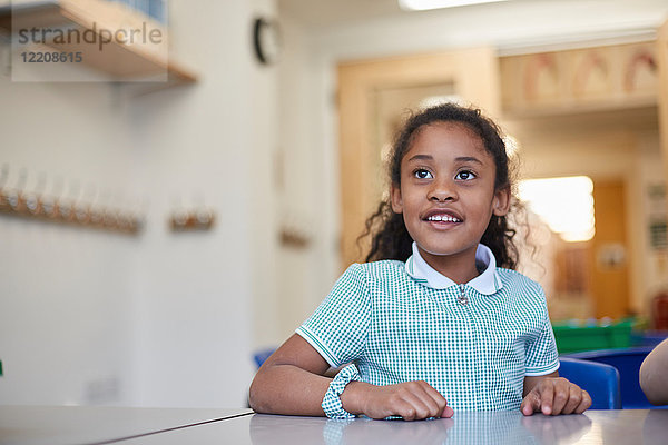 Schulmädchen hört im Klassenzimmer in der Grundschule zu