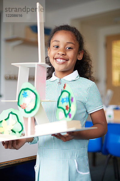 Schulmädchen hält Kartonmodell im Klassenzimmer der Grundschule  Porträt