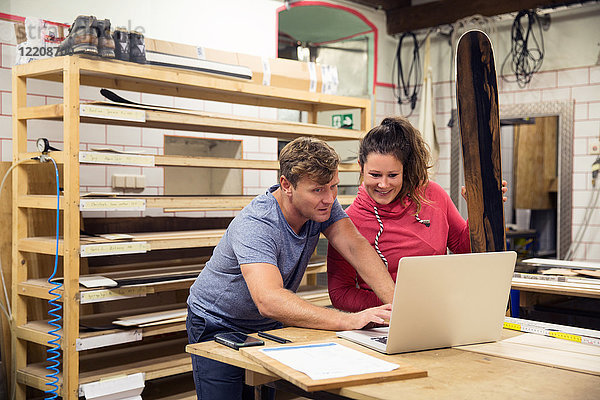 Mann und Frau in der Werkstatt  mit Laptop