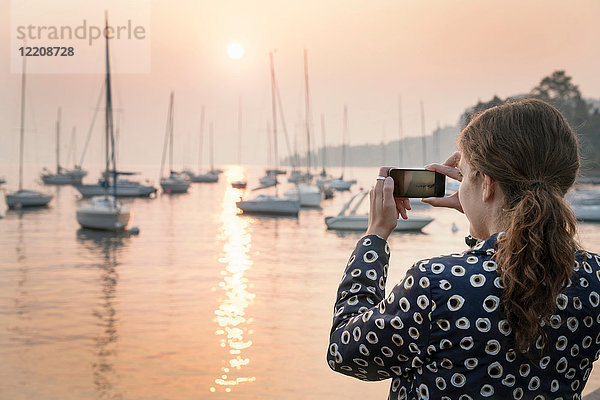 Rückansicht einer Frau  die Boote bei Sonnenuntergang fotografiert  Lazise  Venetien  Italien  Europa