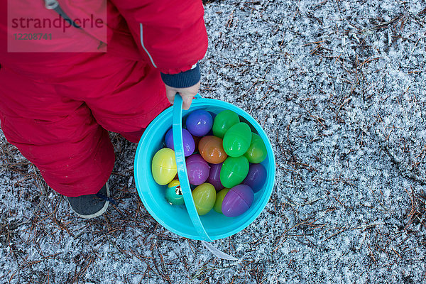 Junge mit Eimer mit Spielzeugeiern