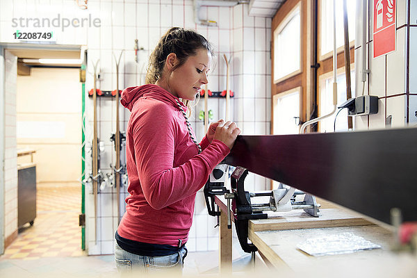 Frau in der Werkstatt  inspiziert Skiausrüstung