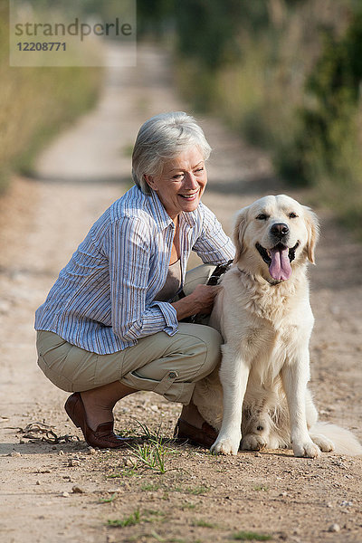 Porträt einer älteren Frau  die neben einem Haushund kauert