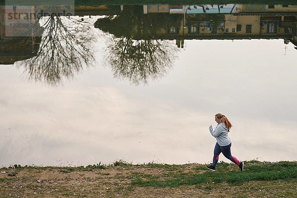 Kurvenreiche junge Läuferin läuft am Flussufer