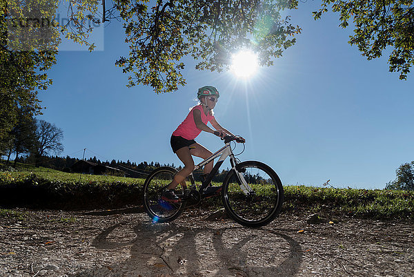 Mountainbike-Mädchen fährt auf sonnenbeschienenem Feldweg