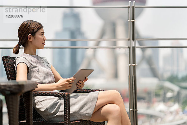 Junge Geschäftsfrau mit digitalem Tablet im Bürgersteig-Café im Finanzzentrum von Shanghai  Shanghai  China