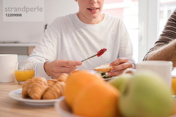 Schnappschuss einer jungen Frau und ihres Freundes mit Croissants am Frühstückstisch