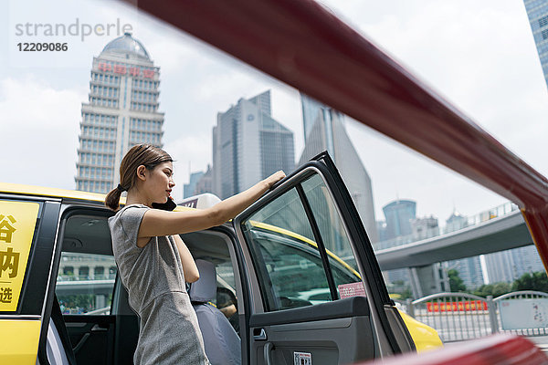 Junge Geschäftsfrau steigt im Finanzzentrum Shanghai aus gelbem Taxi aus  Shanghai  China