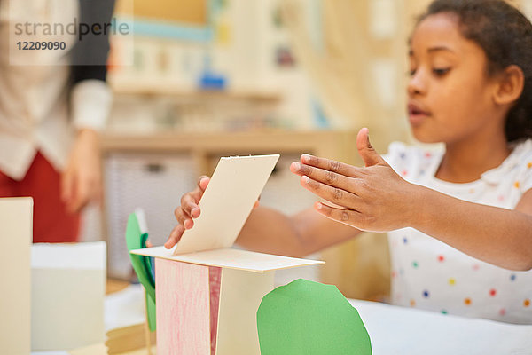 Grundschulmädchen macht Kartonstruktur auf Klassenpult