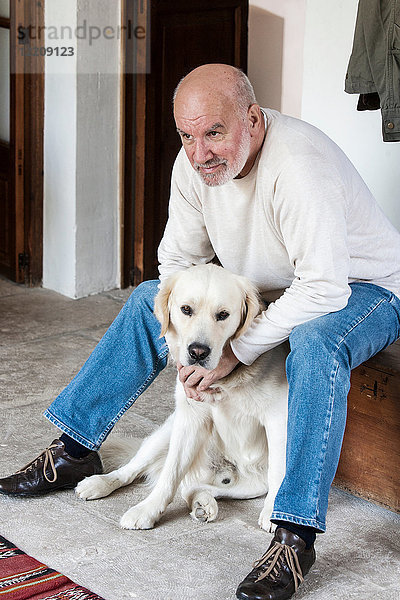 Porträt eines älteren Mannes zu Hause mit Haushund