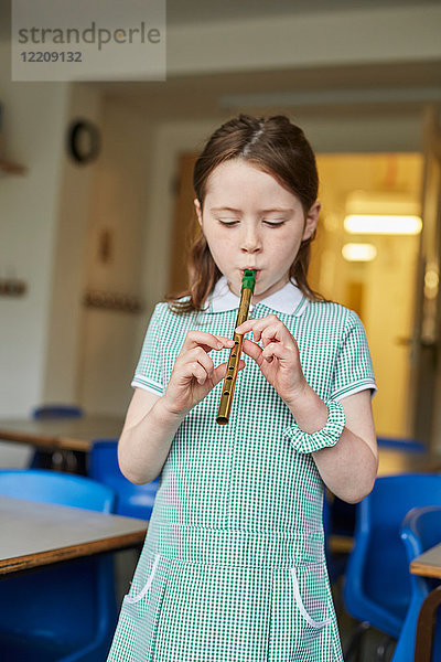 Schulmädchen spielt Blockflöte im Klassenzimmer der Grundschule