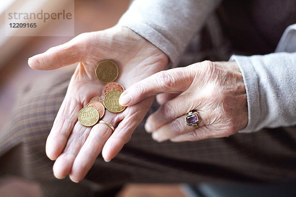 Ältere Frau zählt Münzen in der Hand  Nahaufnahme