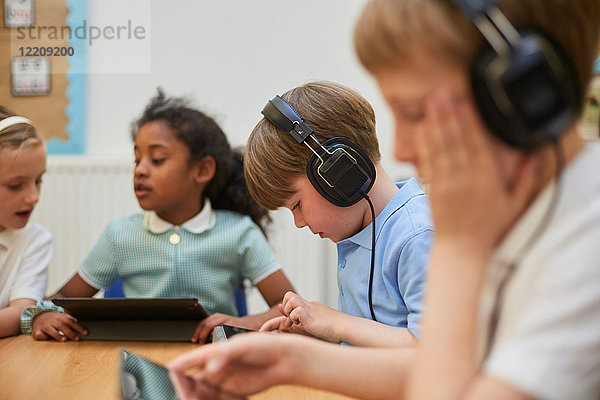 Schülerinnen und Schüler  die in der Grundschule im Unterricht Kopfhörer hören