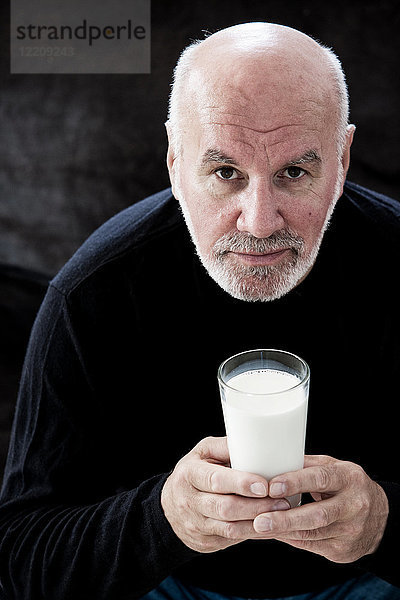 Porträt eines älteren Mannes  der ein Glas Milch hält