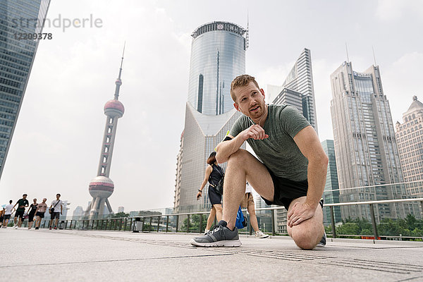 Junger männlicher Läufer macht eine Pause im Finanzzentrum von Shanghai  Shanghai  China