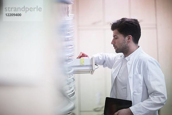 Junger männlicher Apotheker nimmt Pillenflasche aus Apothekenschublade