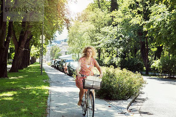 Frau radelt auf dem Fahrrad in einer von Bäumen gesäumten Straße  Innsbruck  Tirol  Österreich  Europa