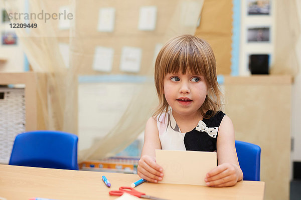 Grundschülerin schaut seitlich vom Klassentisch