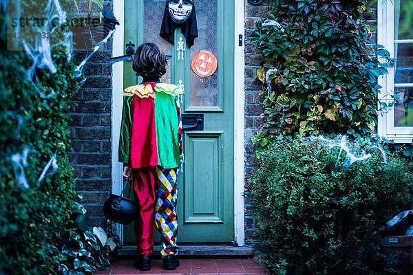 Junge in Halloween-Kostüm  an der Tür stehend  Süßes oder Saures  Rückansicht