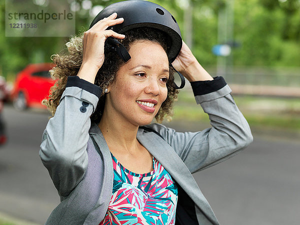 Mittlere erwachsene Frau  die einen Fahrrad-Schutzhelm aufsetzt