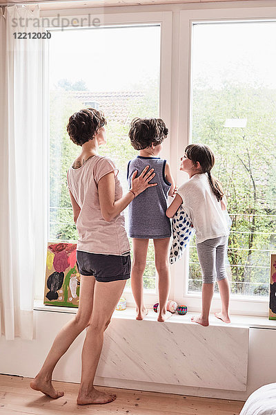 Mutter  Sohn und Tochter zu Hause  Blick aus dem Fenster  Rückansicht