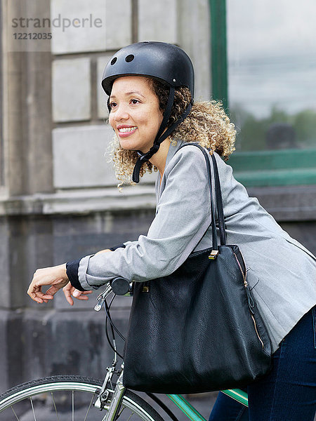 Mittlere erwachsene Frau  die auf dem Fahrrad sitzt und einen Schutzhelm trägt