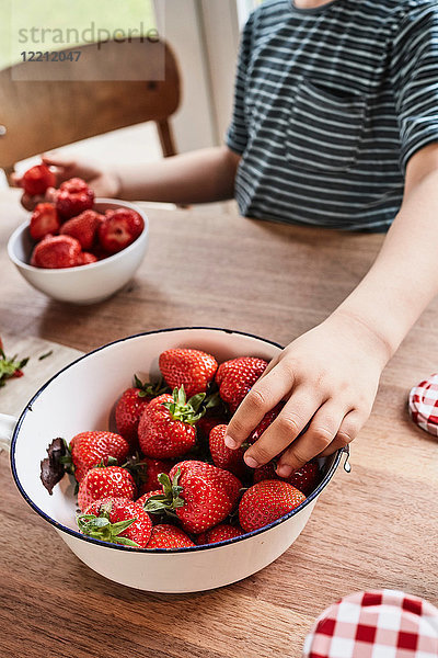 Junge nimmt Erdbeere aus Schale  Mittelteil  Nahaufnahme