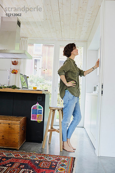 Mittlere erwachsene Frau betrachtet Planer an Küchenwand