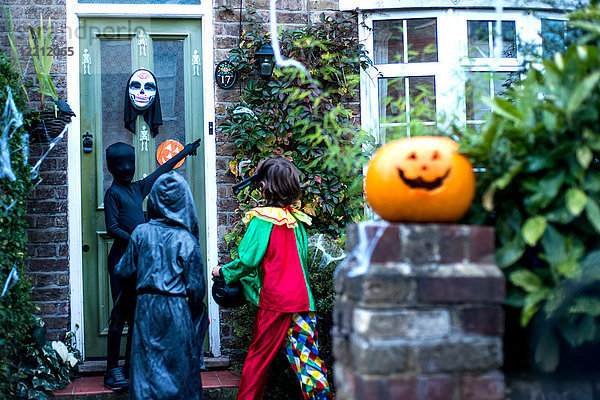 Drei Jungen in Halloween-Kostümen  an der Tür stehend  Süßes oder Saures  Rückansicht