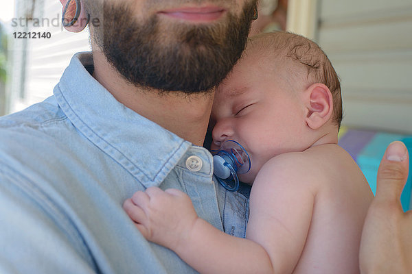 Mann mit schlafendem Jungen auf der Schulter