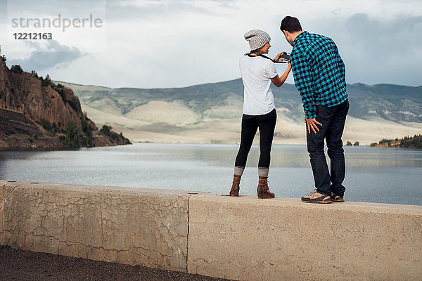 Ehepaar steht an der Wand neben dem Dillon-Stausee und schaut in die Kamera  Rückansicht  Silverthorne  Colorado  USA