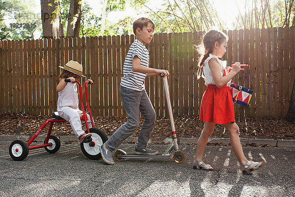 Drei Kinder in Mini-Parade  Trommelschlagen  Dreiradfahren und Rollerfahren