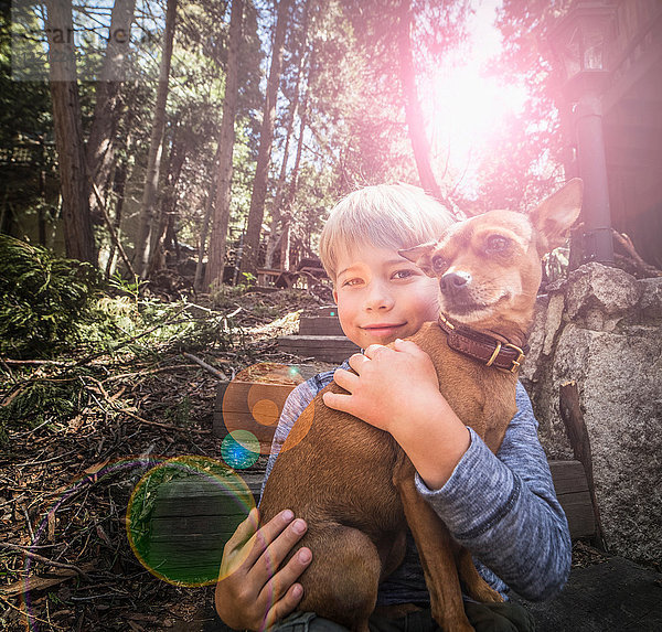 Junge trägt Hund im Wald