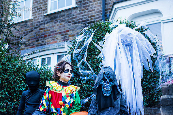 Junge Burschen in Halloween-Kostümen  neben Haus  Trick oder Behandlung