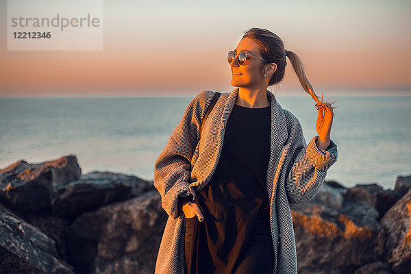 Porträt einer Frau mit Sonnenbrille und Wintermantel  die lächelnd wegschaut  Odessa  Odeska Oblast  Ukraine  Osteuropa