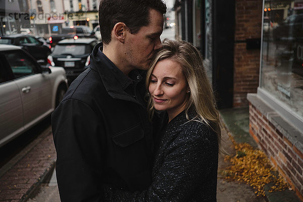 Mittelgroßes erwachsenes Paar umarmt sich auf der Straße