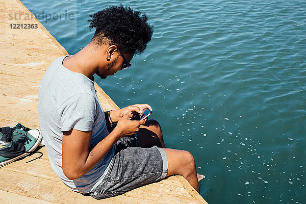 Mann benutzt Mobiltelefon am Wasserrand