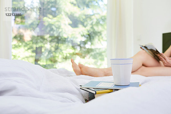 Frau  entspannt im Bett  Lesebuch  Unterteil  Bücher und Kaffeetasse im Vordergrund