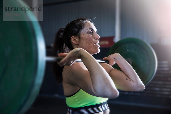 Frau übt im Fitnessstudio  mit Langhantel